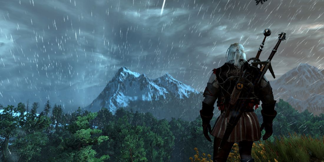 Third-person view of Geralt standing in the rain, looking at a snow-capped mountain across a forest in The Witcher 3.