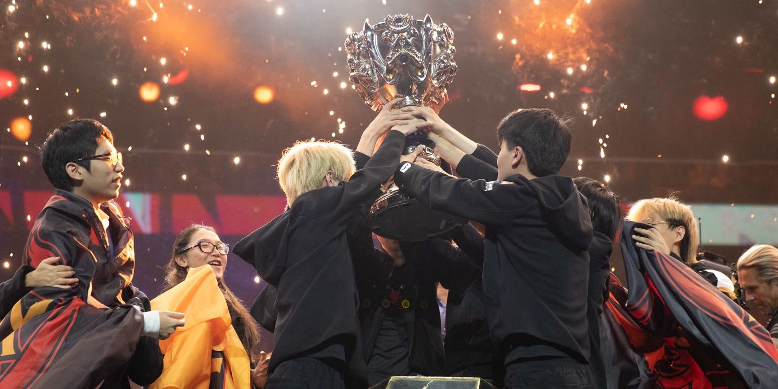 FunPlus Pheonix Holding Up Trophy Together With Flags Draped Over Their Shoulders Huddled