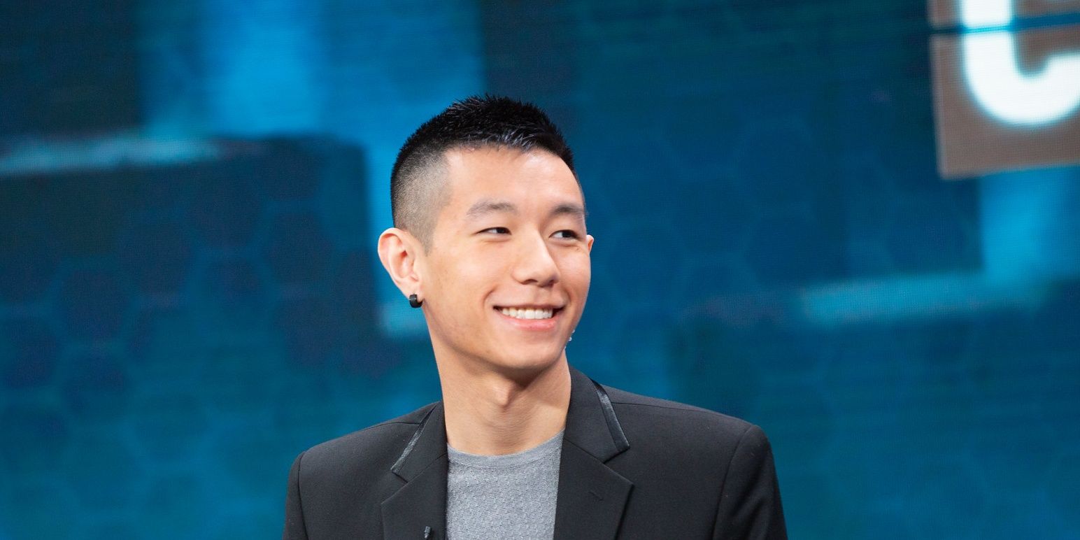 League Of Legends Hai Smiling Looking Over At Colleagues While On The Analyst Desk