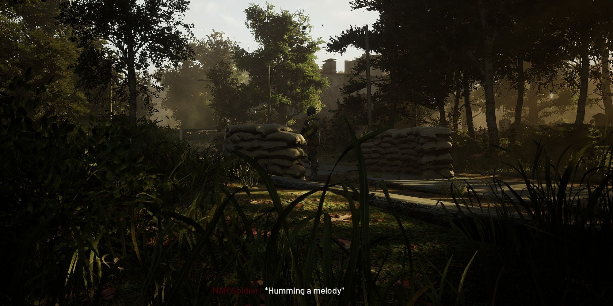 Chernobylite: a guard at guardpost hums unaware by some sandbags. 