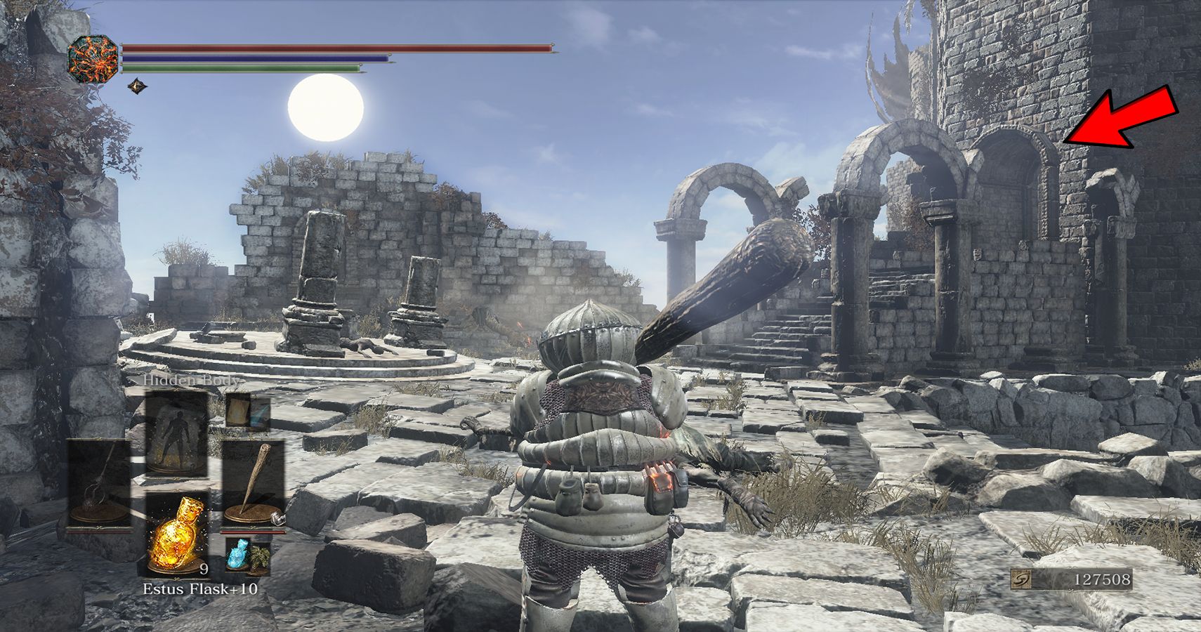 player standing in ruins with arrow pointing to nearby doorway