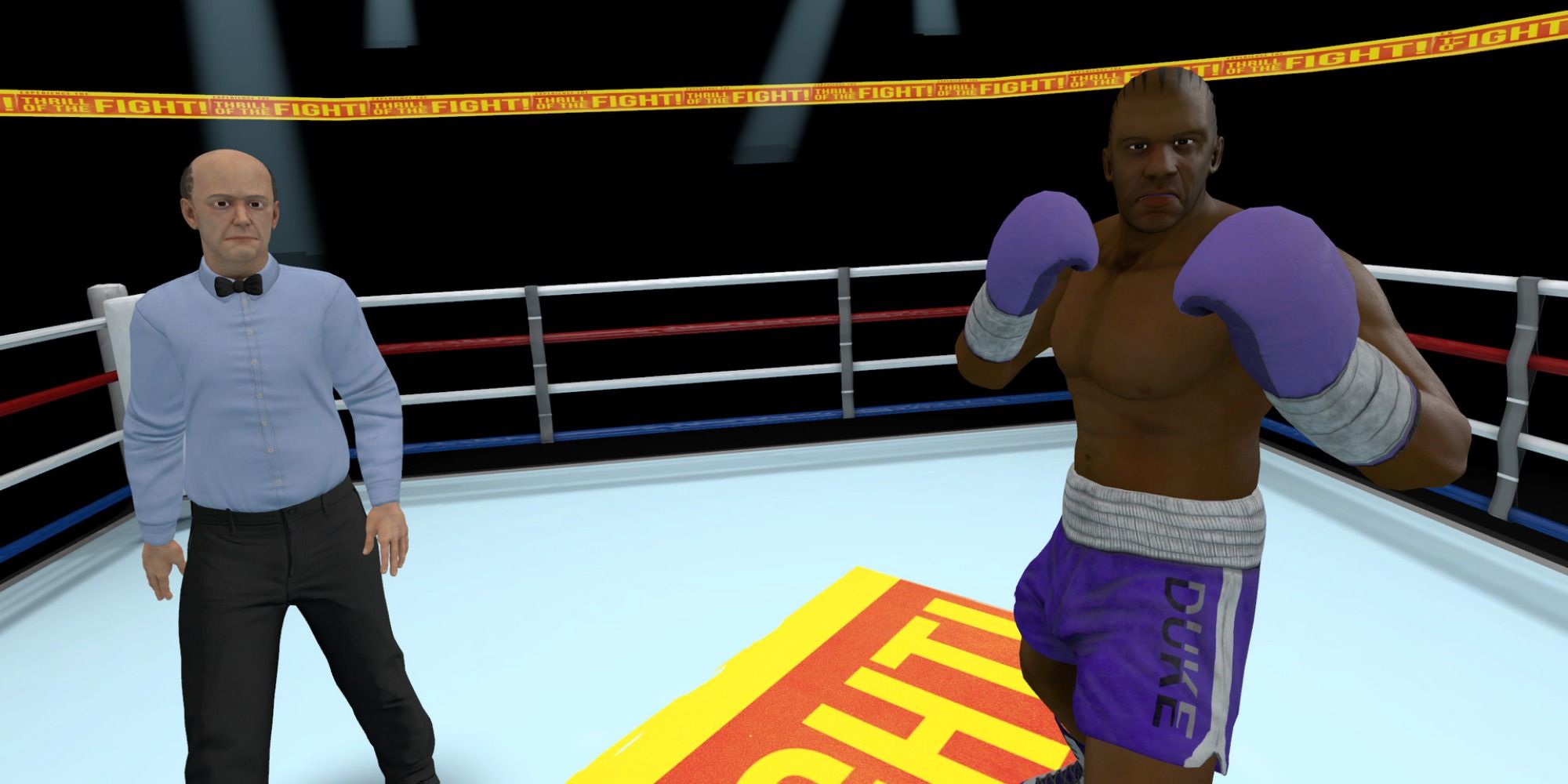 A man wearing blue boxing gloves and shorts stands with hands up ready to fight in a boxing ring, while to the side a referee in a bow tie oversees