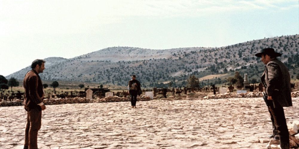 Three men stand off facing each other in a large dry deserted graveyard