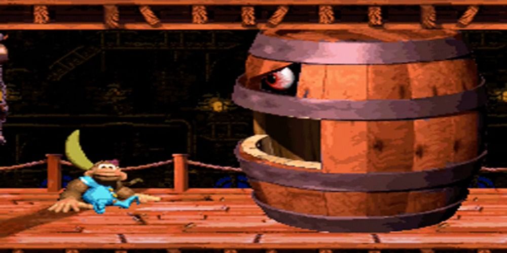 A large baby gorilla sits in front of a giant barrel with evil eyes