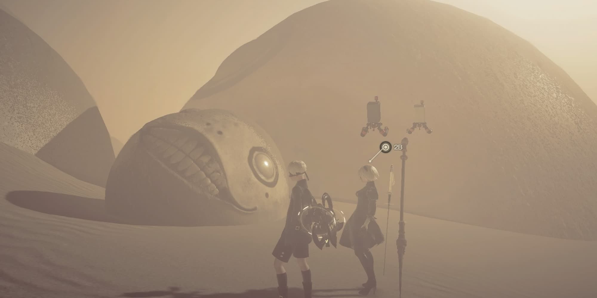 2B and 9S looking at a giant Emil head in the desert