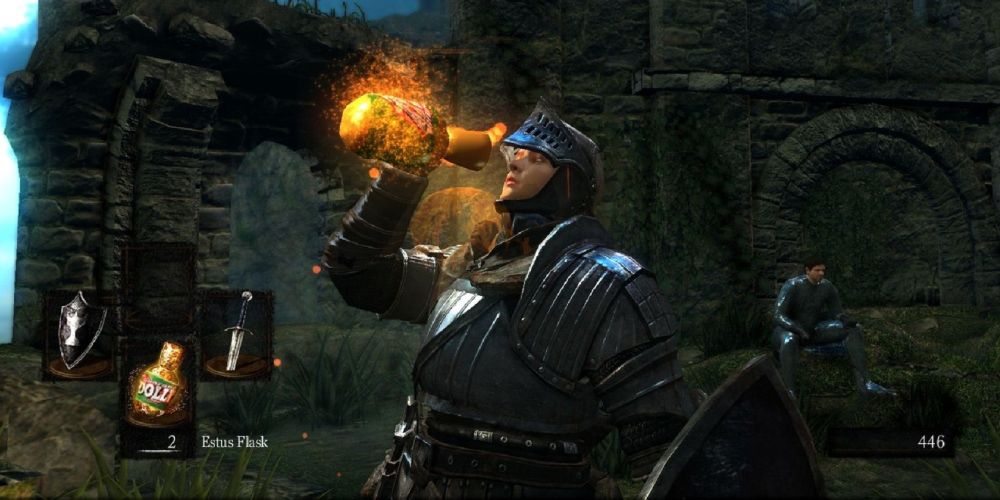 a mid shot of someone drinking from an estus flask with a character sat in the background and a radial menu showing a shield, estus flask and sword on the left