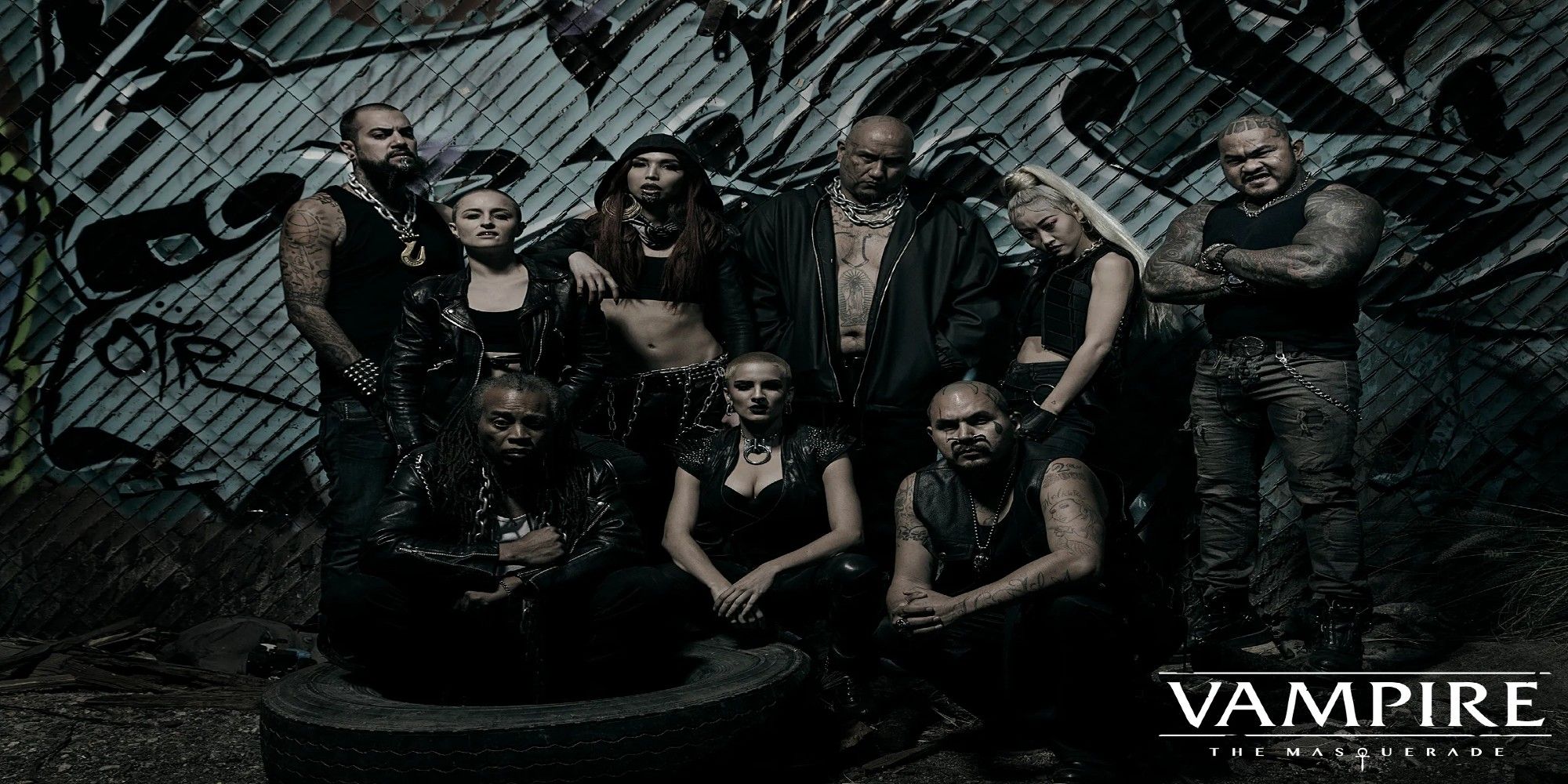 A group of biker-looking people stand in front of graffiti