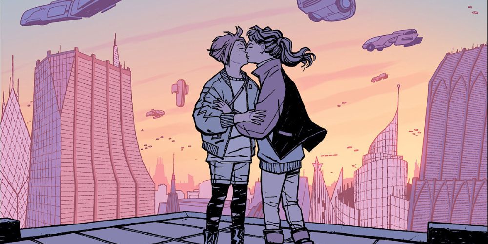 a frame from a Paper Girls comic featuring two of its protagonists, KJ and Mac, kissing against a backdrop of a futuristic city