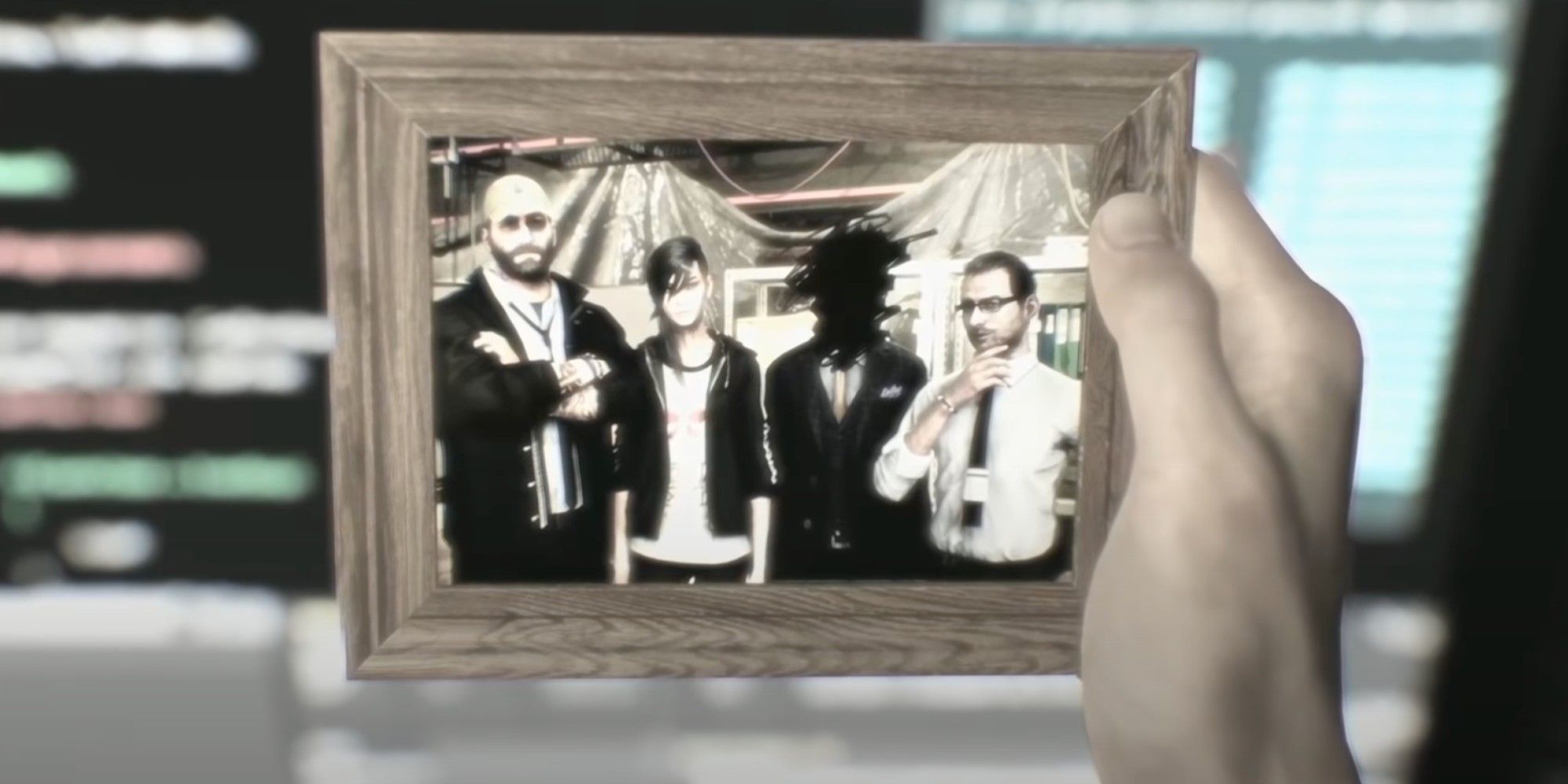 A hand holding a framed picture of a group of investigators from the recent past.