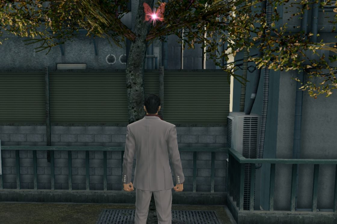 Yakuza Kiwami screenshot. Kiryu stands under a tree with a glowing red butterfly in it.
