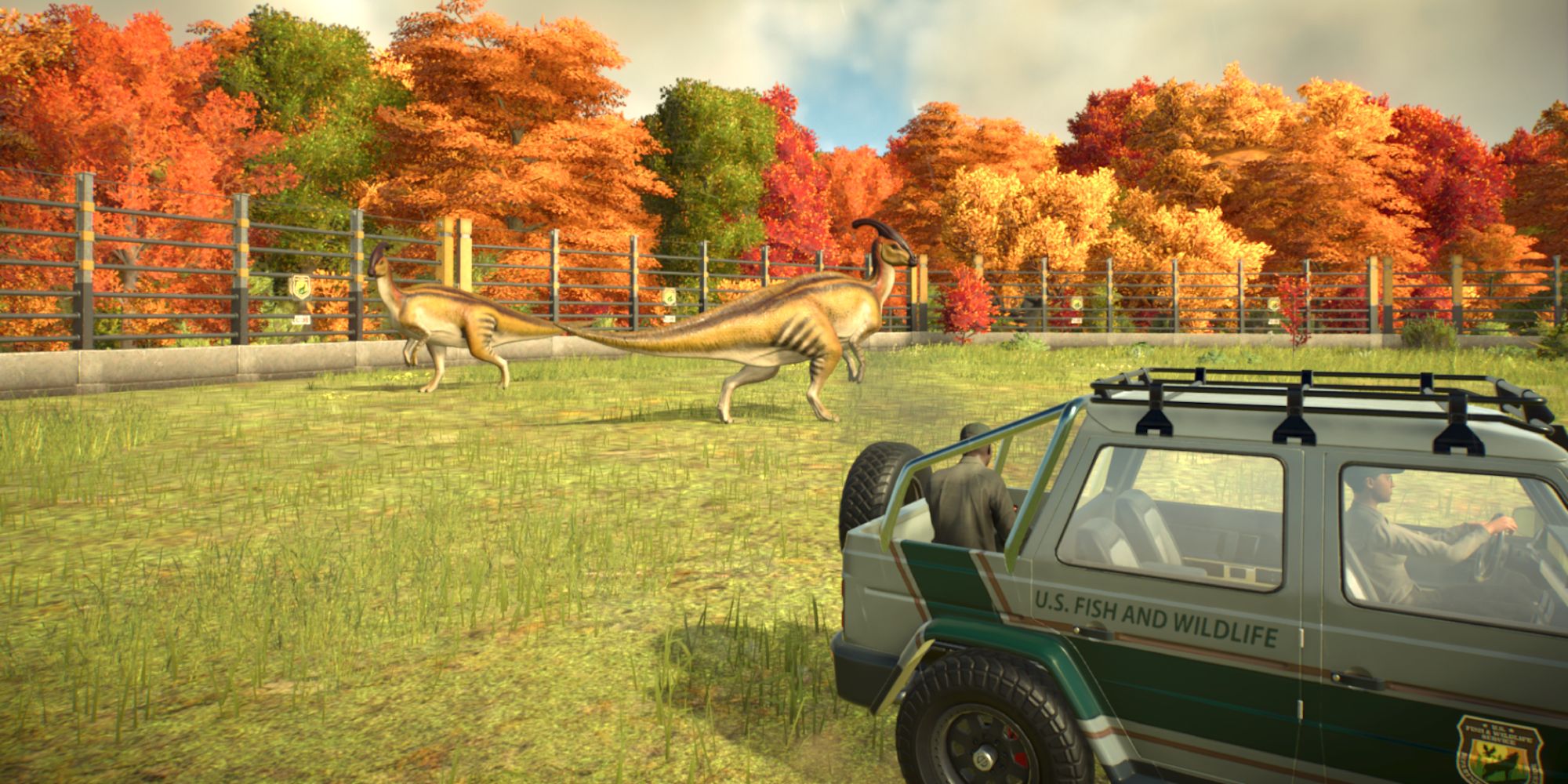 a wide shot of a jeep driving by two towering dinosaurs with autumnal trees in the background behind the electrified fences