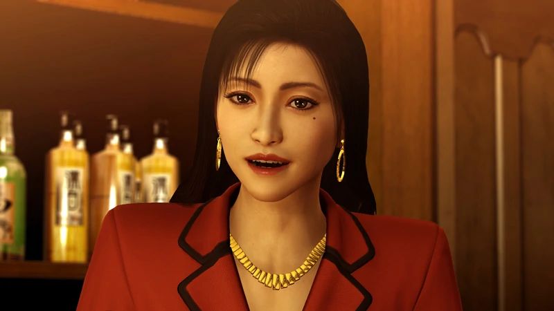 Reina standing in a red suit with a gold necklace, smiling