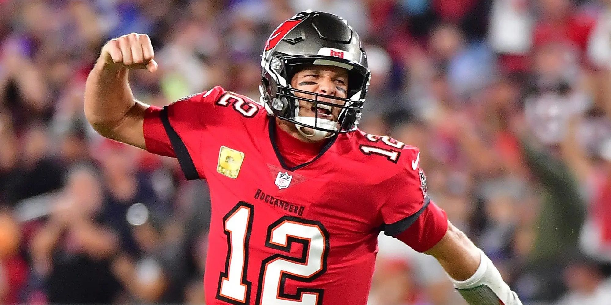 Tom Brady fist pumping and screaming in a red Buccaneers jersey