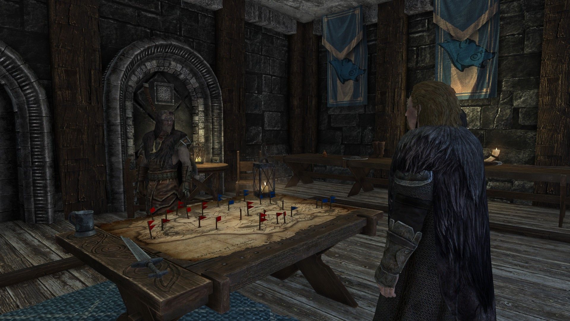 Two military commanders stand over map table inside their castle. Blue banners hang in the background.