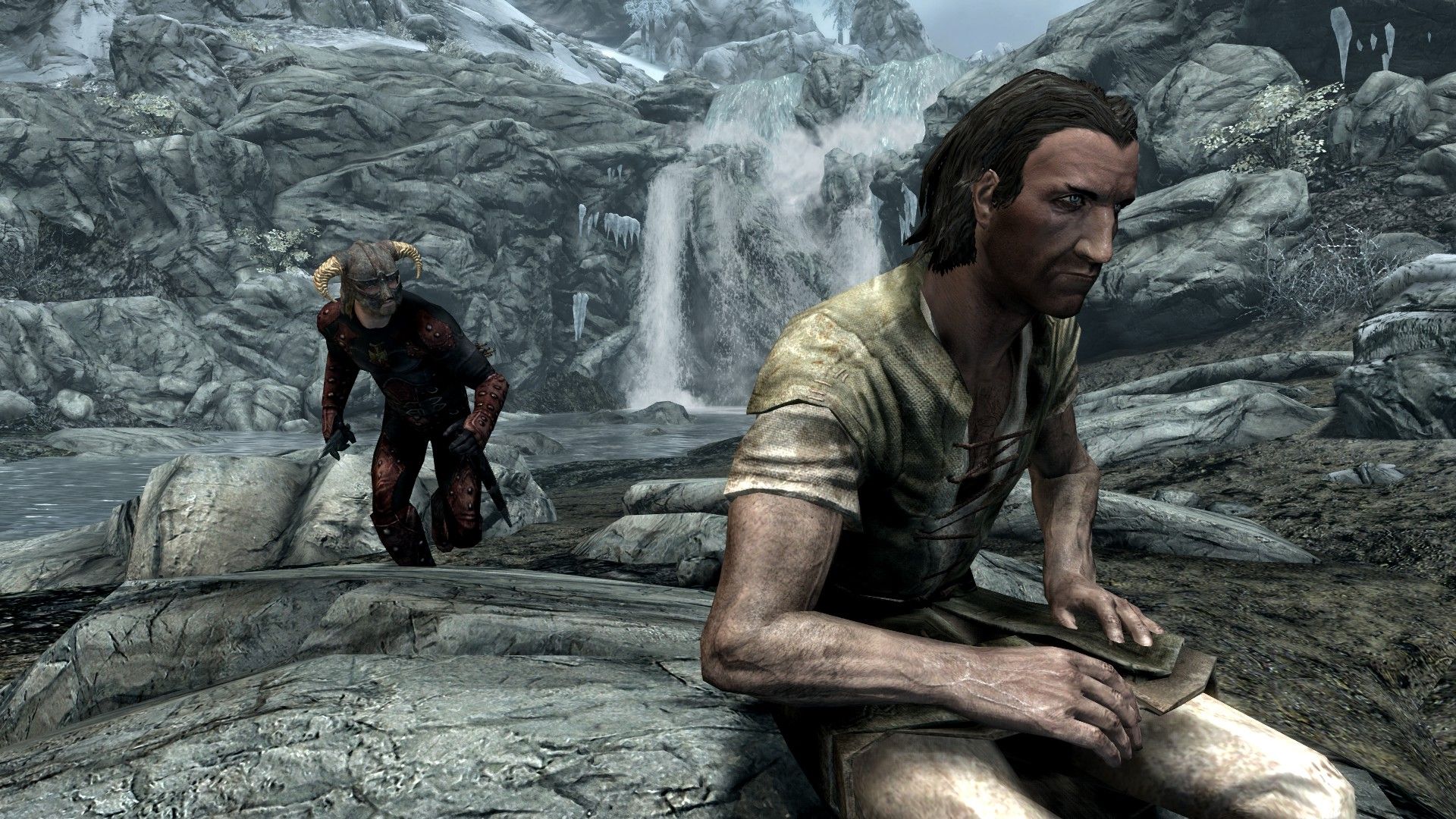 A man sneaks up behind a man sitting on a log in a snowy wilderness.