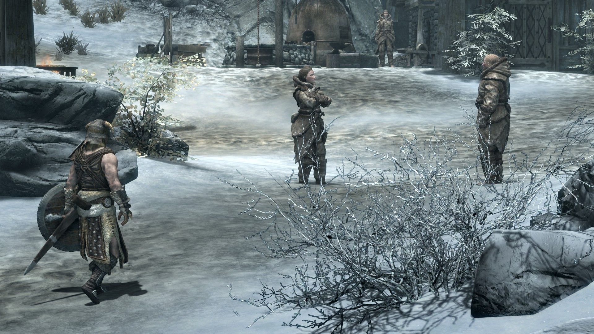 A man walks over to a pair of villagers dressed to survive the frigid cold of their home.