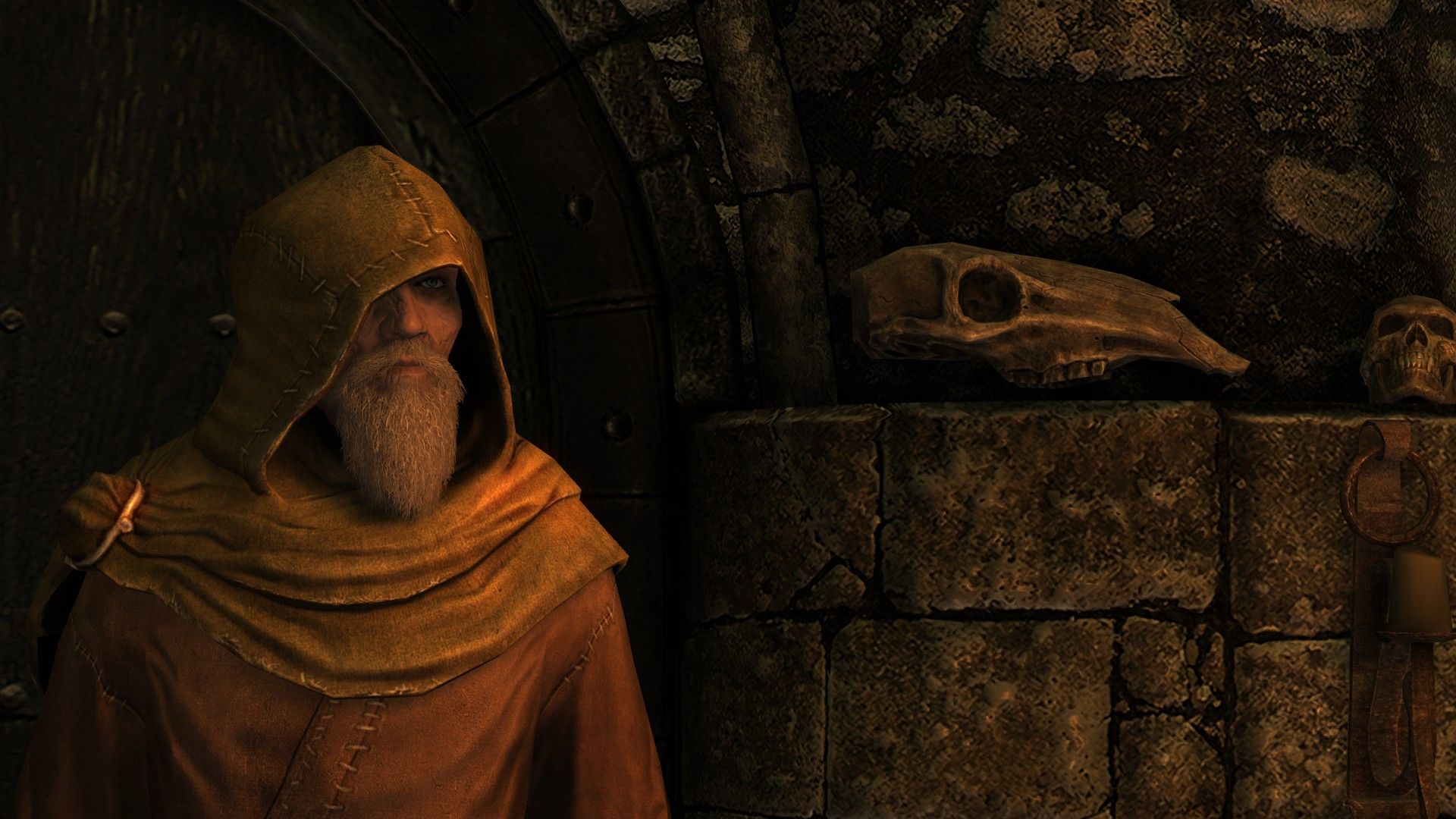A man dressed in yellow robes stands in a stone building with an animal skull behind him.
