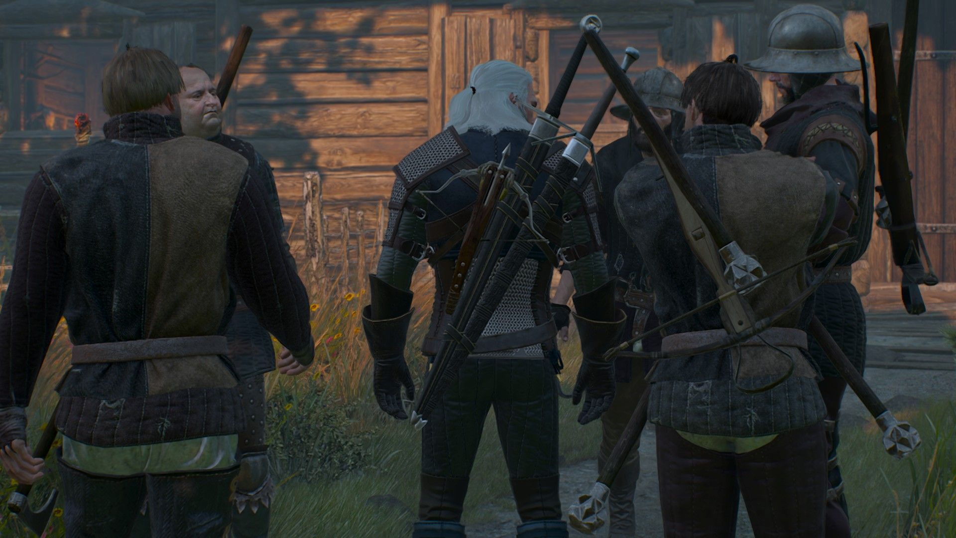 Geralt stands outside a house, surrounded by a gang of heavily armed bandits.