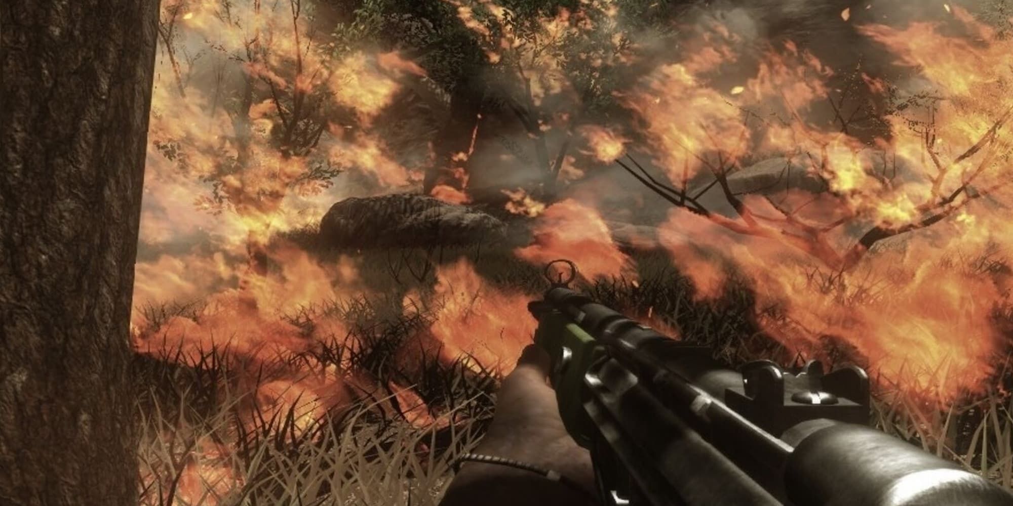 The player, with a submachine gun in hand, watches as a fire engulfs a forest.