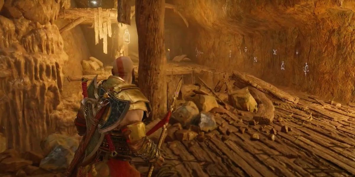 Kratos facing a rock wall with runes and a ledge