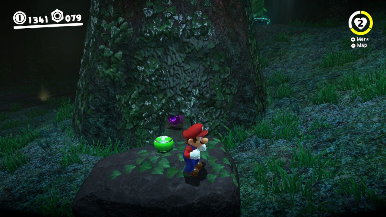 Mario moves a rock out of the way to find some purple coins under a tree in the Deep Woods in Super Mario Odyssey.