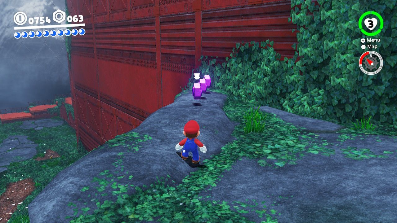 Mario standing on a rock with purple coins in front of him in the Wooded Kingdom in Super Mario Odyssey.