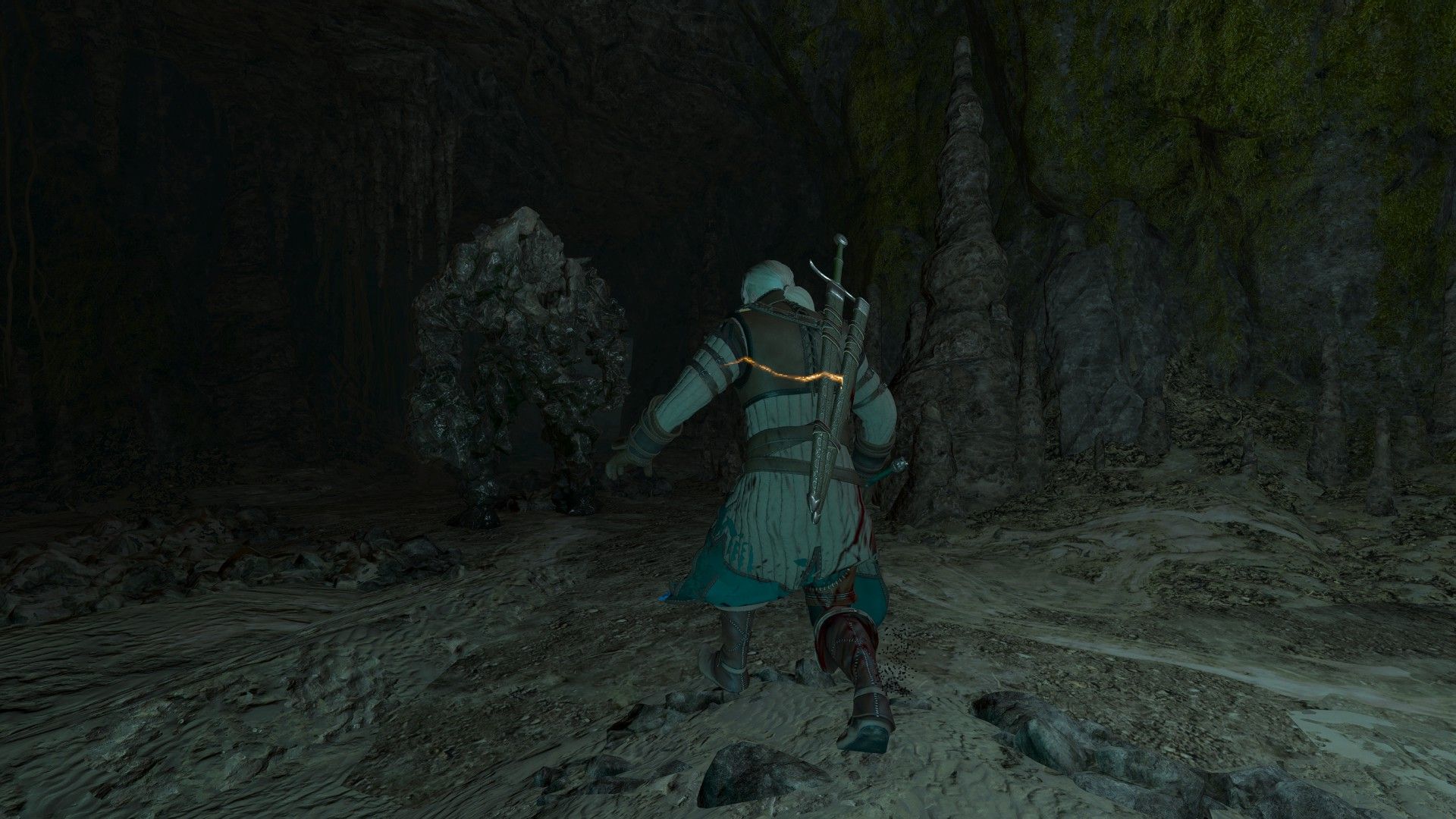 Geralt approaches a rock-like monster in a dark cave with his silver sword drawn and a defensive spell circling him.