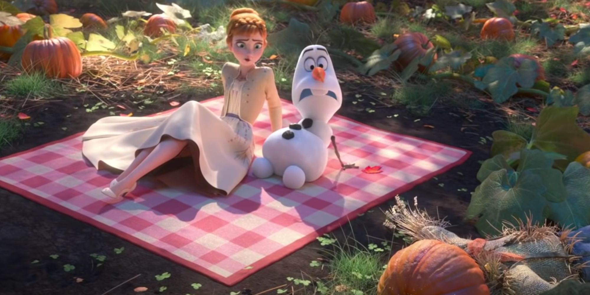 Olaf and Anna having a picknick in a meadow on a blanket while looking worried at a pumpkinhead straw scarecrow on the ground.