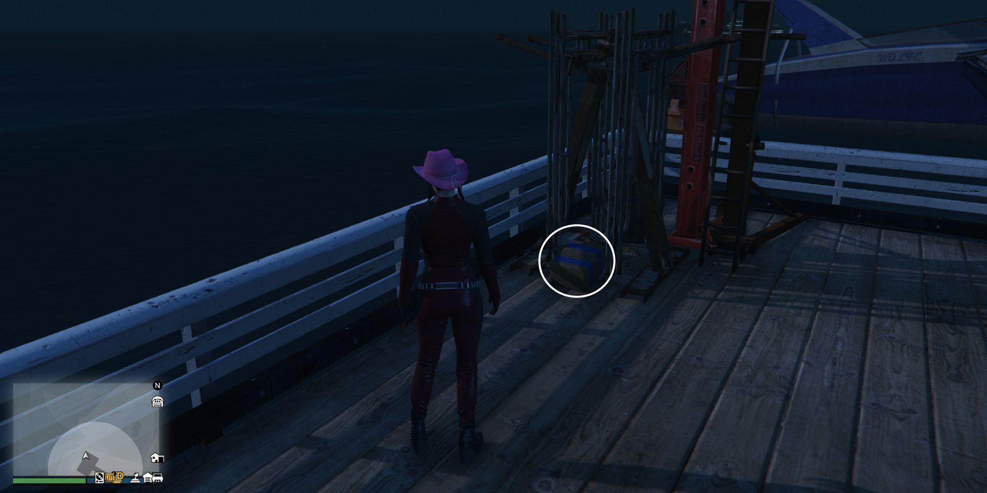 Image depicts a female player in GTA Online at the Chumash Historic Family Pier infront of some metal equipment at the end of the dock. At the foot of the silver piece of equipment is G's Cache.