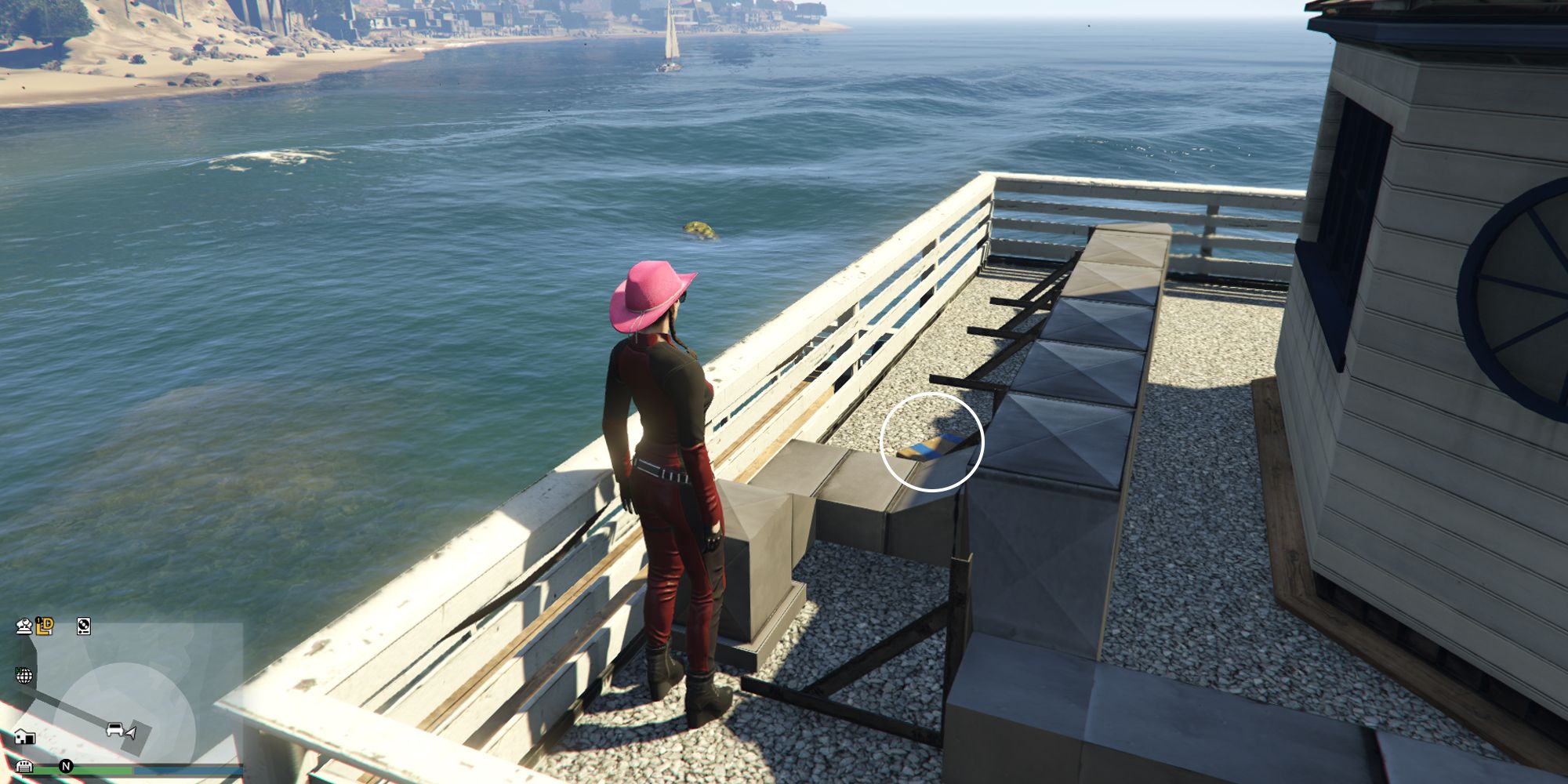 Image depicts a female player in GTA Online at the Chumash Historic Family Pier on top of one of the buildings at the end of the dock. There are a series of vents on top of the building, and G's Cache is sat among these vents.