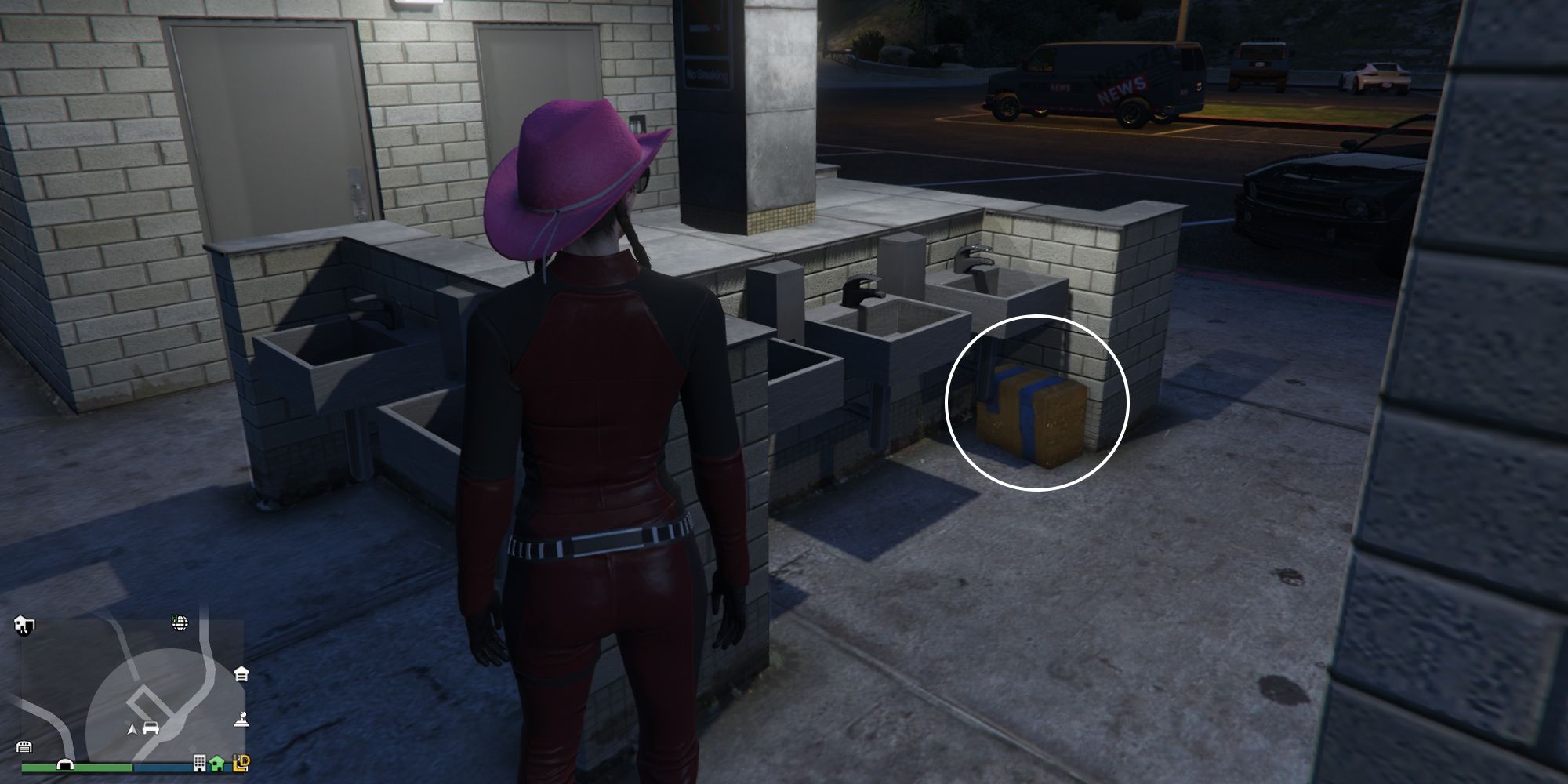 Image depicts a female player in GTA Online at the Galileo Observatory stood by the toilet block that overlooks the car park for the area. There are a series of sinks in the middle of the block, and G's Cache is located under one of the three sinks on the Southern side of the area.