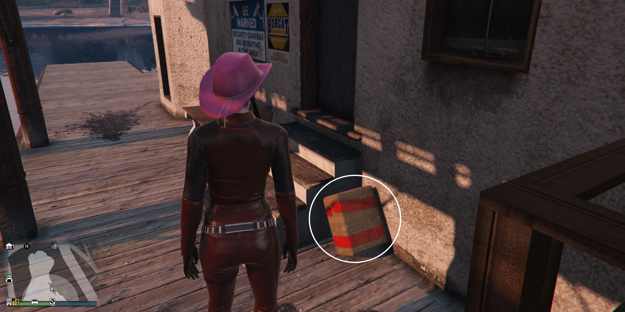 Image depicts a female player in GTA Online at the Mirror Park Lake at the lake house in the centre of the area. There are a set of steps by the front door, and G's Cache is perched against these steps.