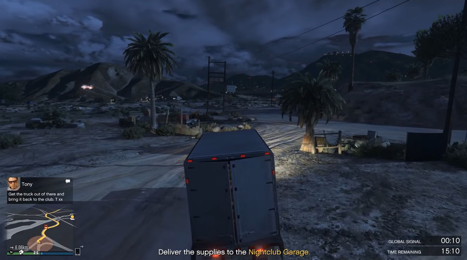 Image depicts a player in Grand Theft Auto Online driving a white van through a sandy area in Sandy Shores. On the left of the screen is a text from Tony that reads 'Get the truck out of there and bring it back to the club. T xx' with a mini map underneath that with a yellow route. In the centre of the screen it reads 'Deliver the supplies to the nightclub garage'. On the bottom left of the screen is a timer reading 15:10.