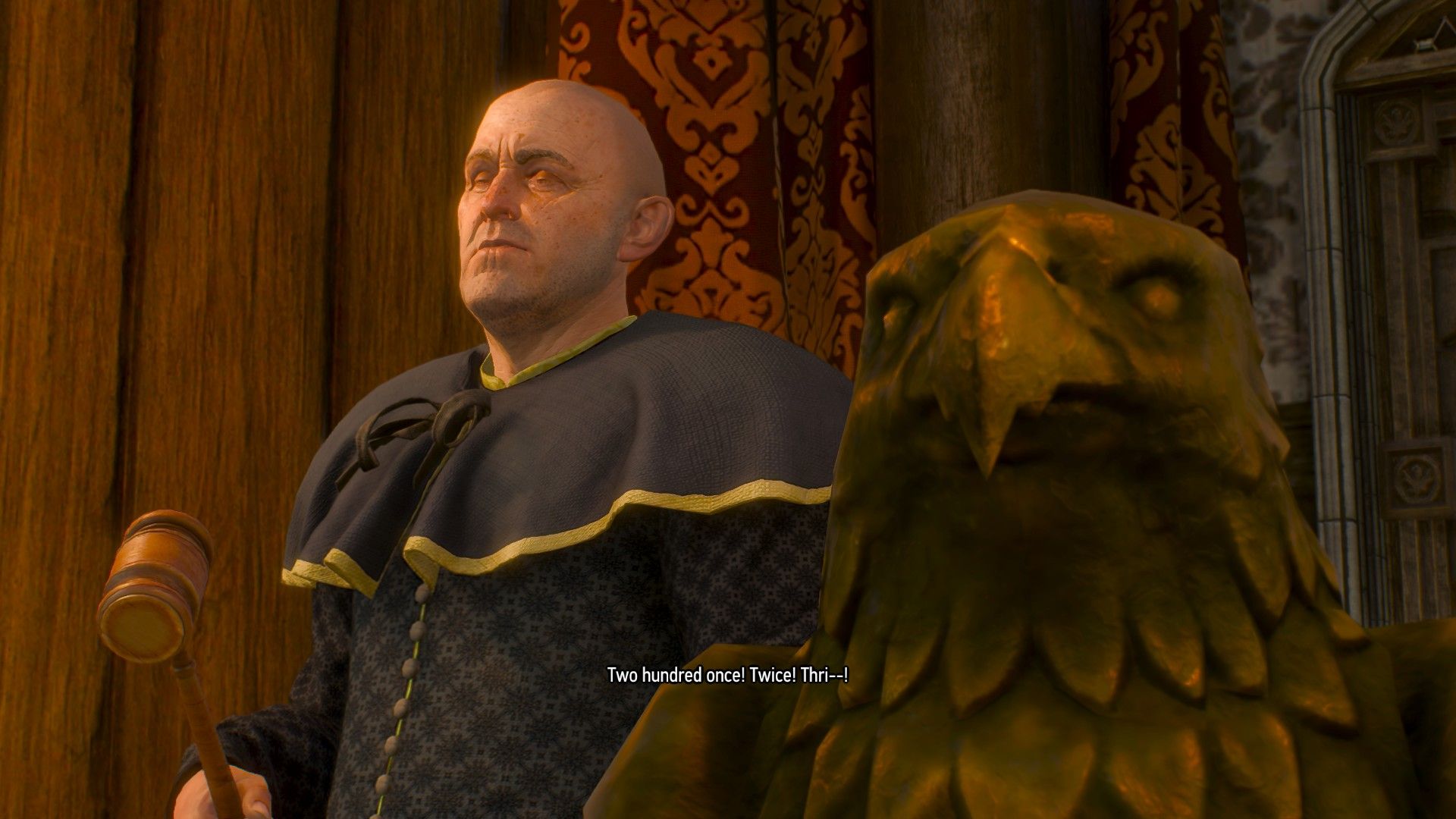 A man presents an eagle-like wooden statuette at an auction house.
