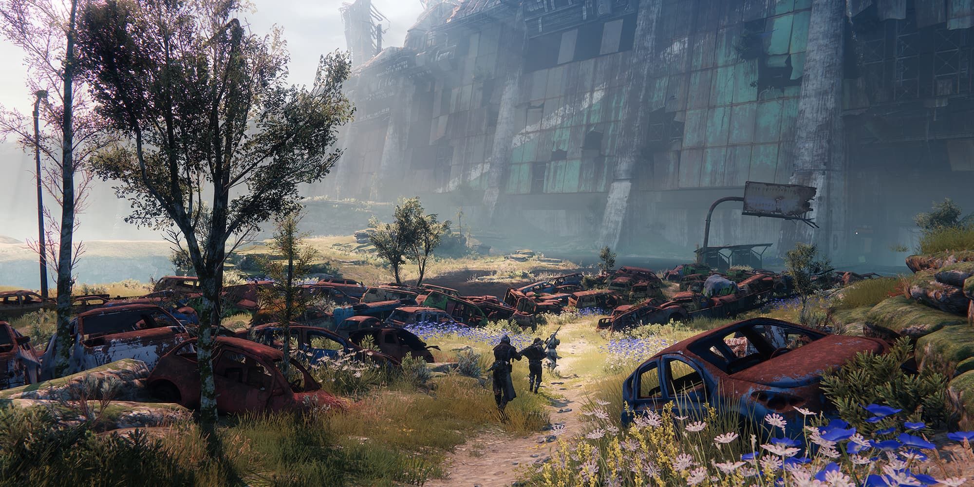 Players walk towards a broken down building along a path lined with rusted vehicles in Destiny 2.