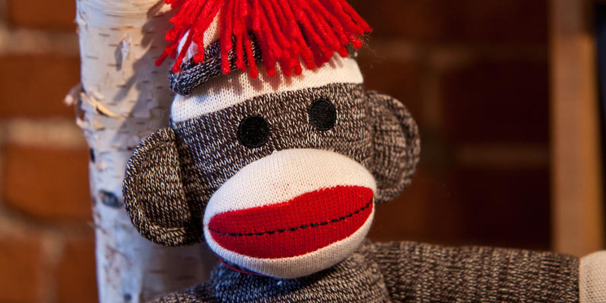 sock monkey up close of face leaning against stick