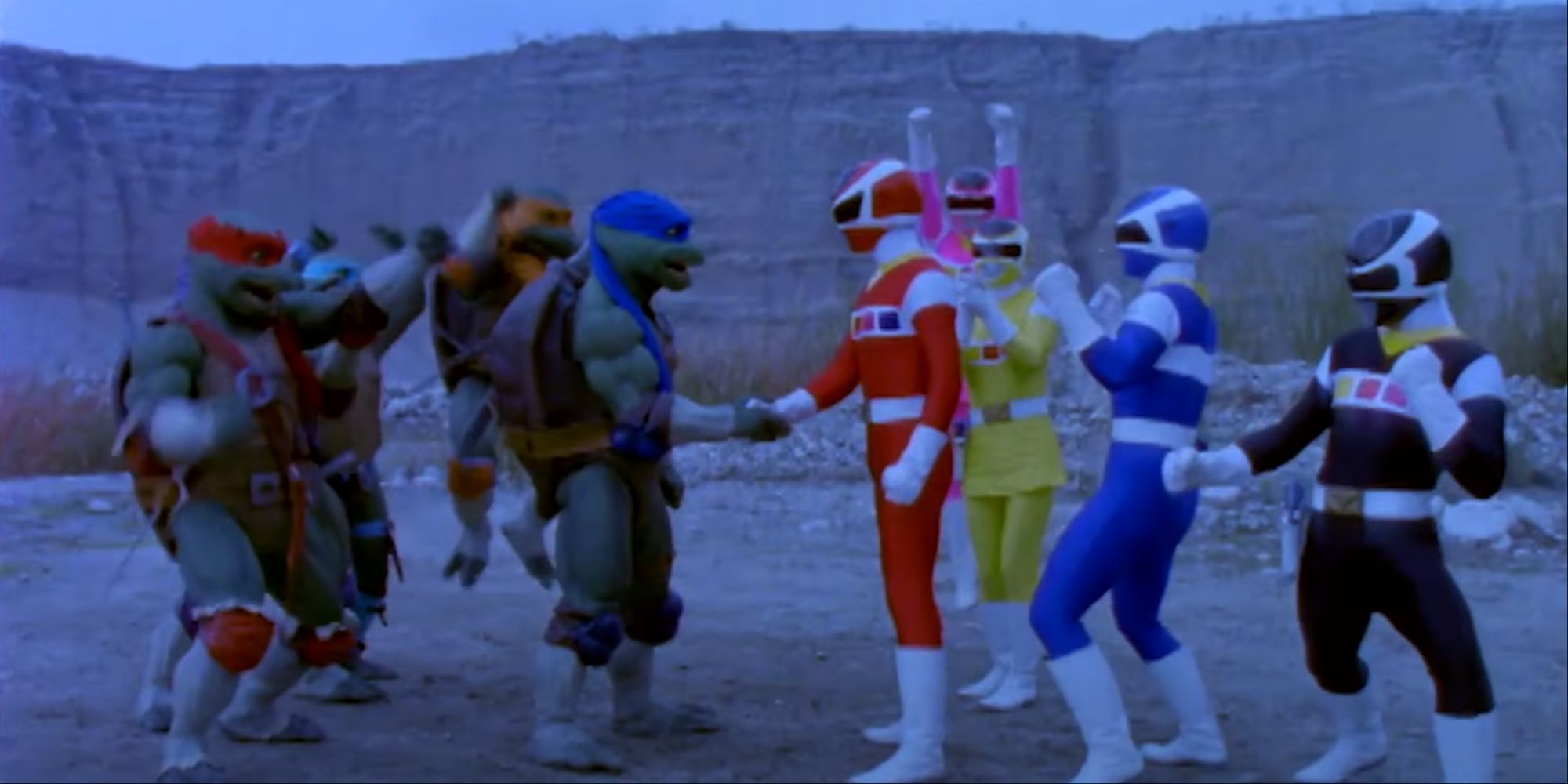 Leonardo shaking the red Power Ranger's hand while the rest of the TMNT and Power Rangers are cheering.