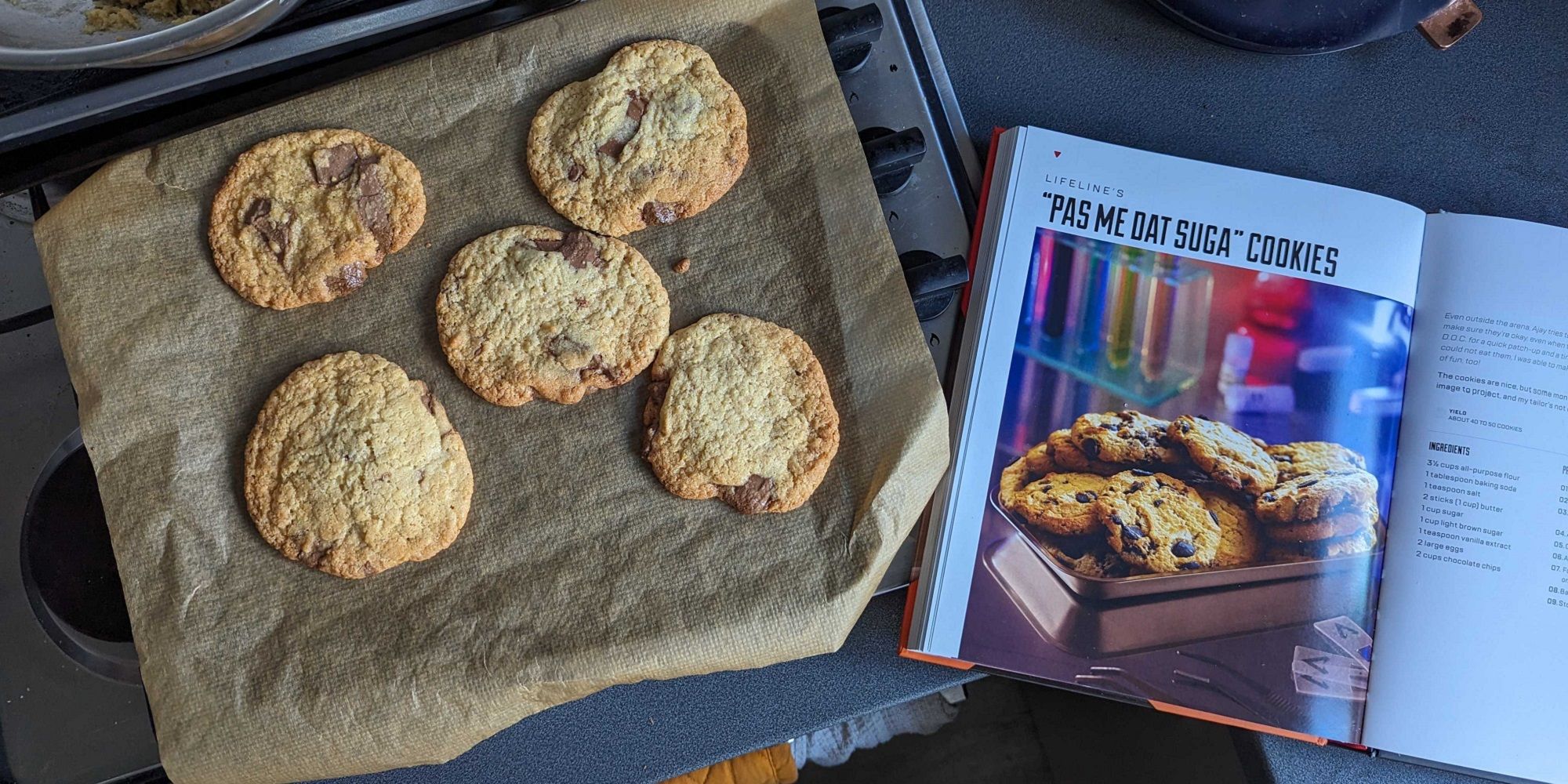 a tray of cookies next to the apex legends cookbook open on the recipe page