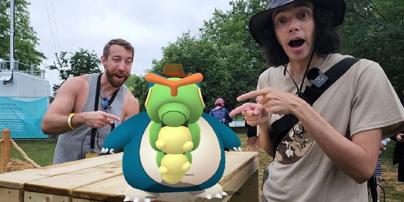 A caterpie stood in front of a Snorlax with a cowboy hat in Pokemon Go's AR mode, with trainers standing and pointing at it