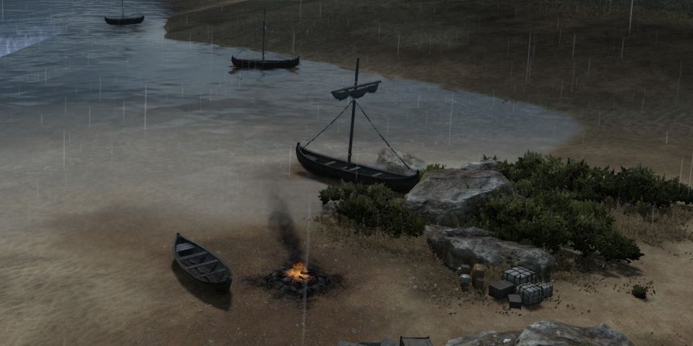 a camp on a riverside battlefield, with the fire burning and boats anchored, in Total War: Pharaoh