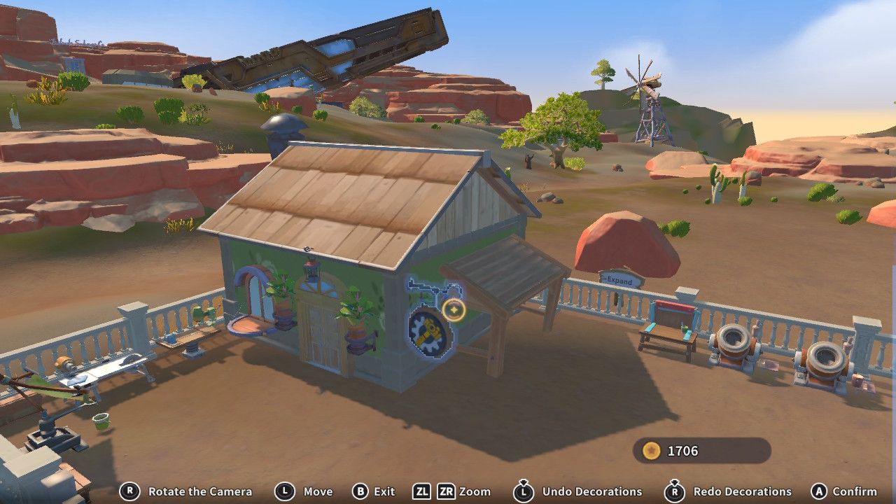 Player character in the Construction Junction build mode and putting a round sign with a hammer on it on the side of their green house near a wooden portico in My Time Time At Sandrock.