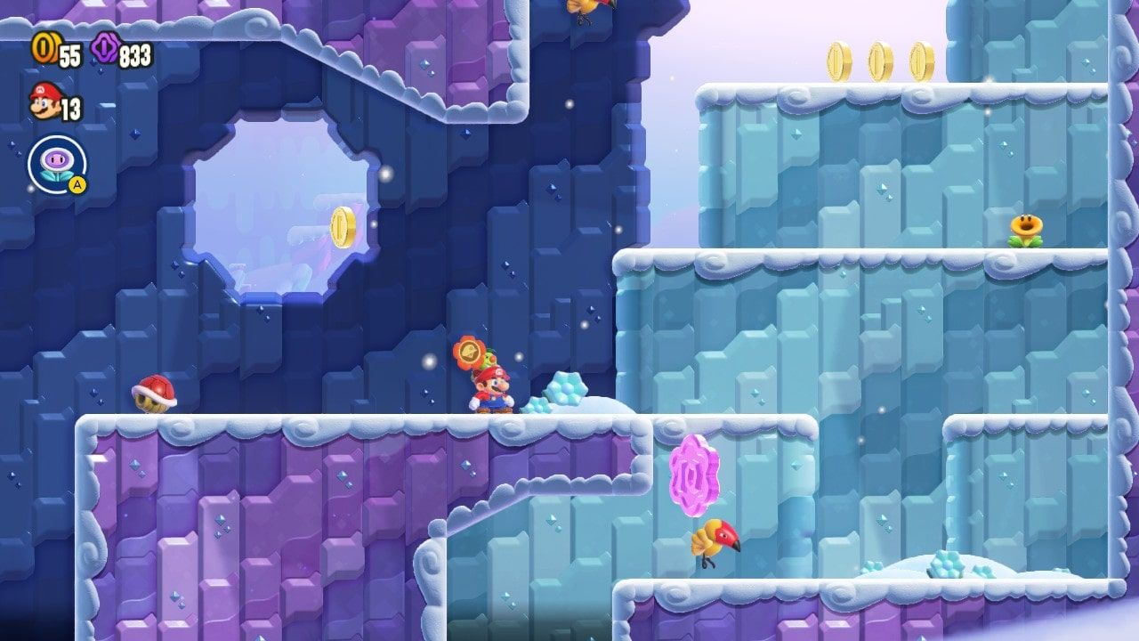 Mario standing in a blue cave with snowy steps leading up into the light. A condart guards a large purple coin in the bottom right corner.