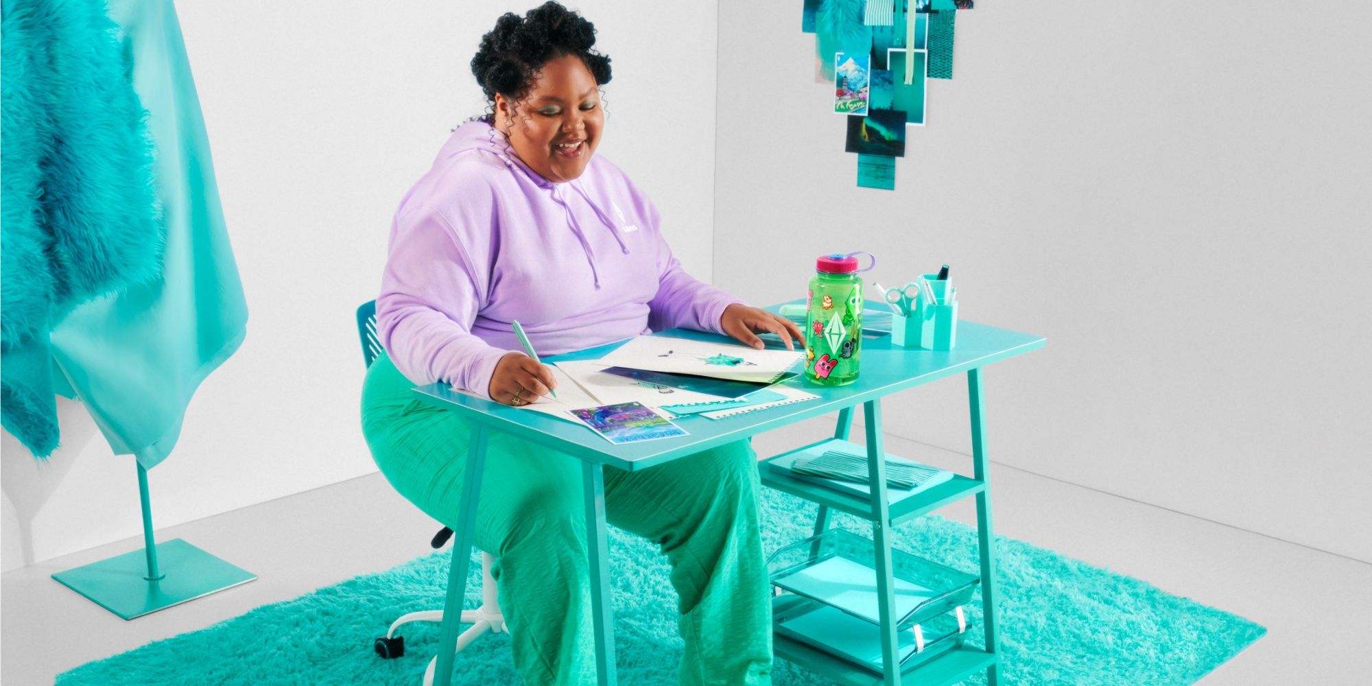 woman sitting at a desk wearing sims merch with a sims water bottle