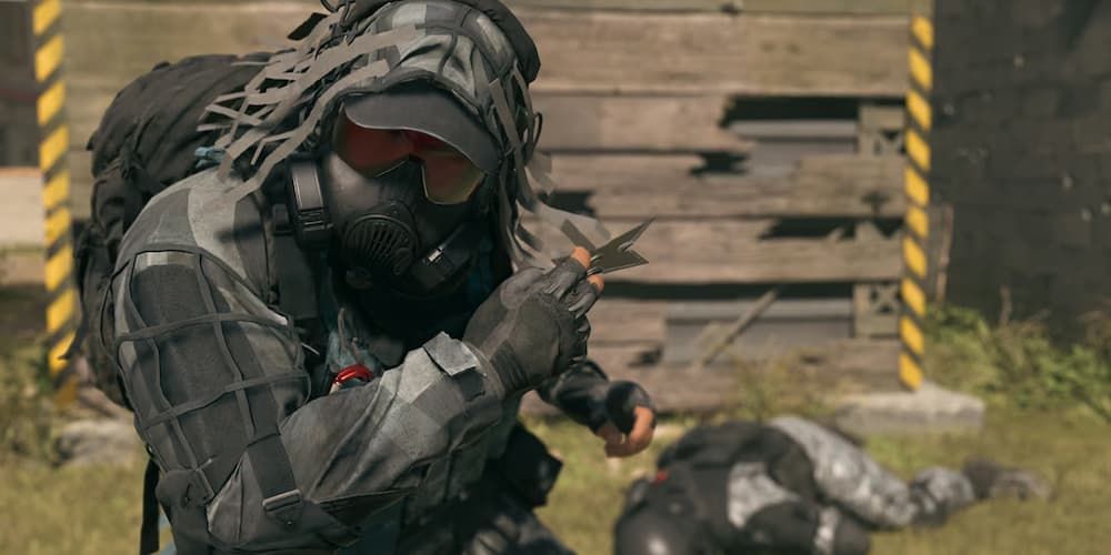 An operator holding onto a Throwing Star with an enemy defeated in the background in Call of Duty: Modern Warfare 3.