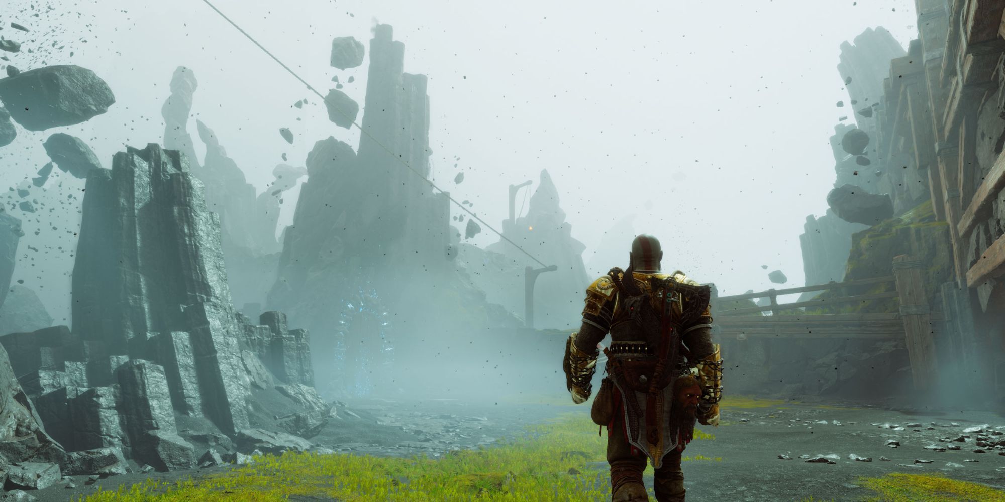 Kratos walks through a foggy open area surrounded by mountains