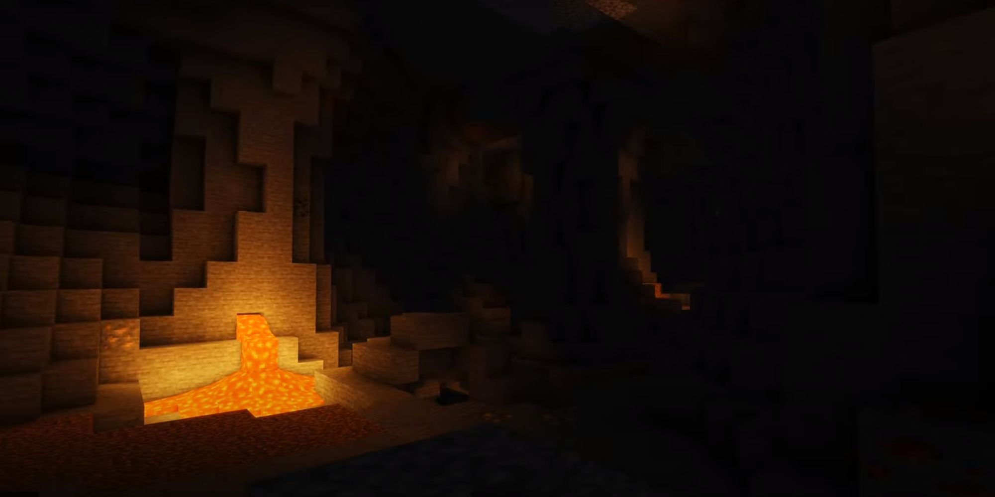 A dark cave illuminated by a small spout of lava.