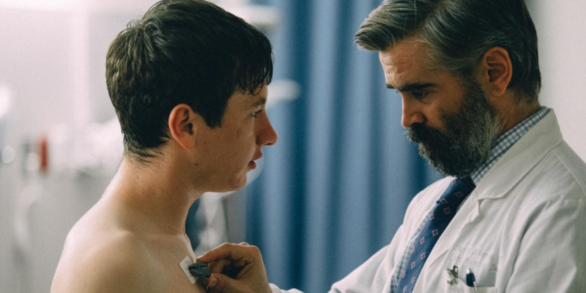 Colin Farrell's character Steven removing the EKG readers and patches from Martin's body after an examination in a hospital room