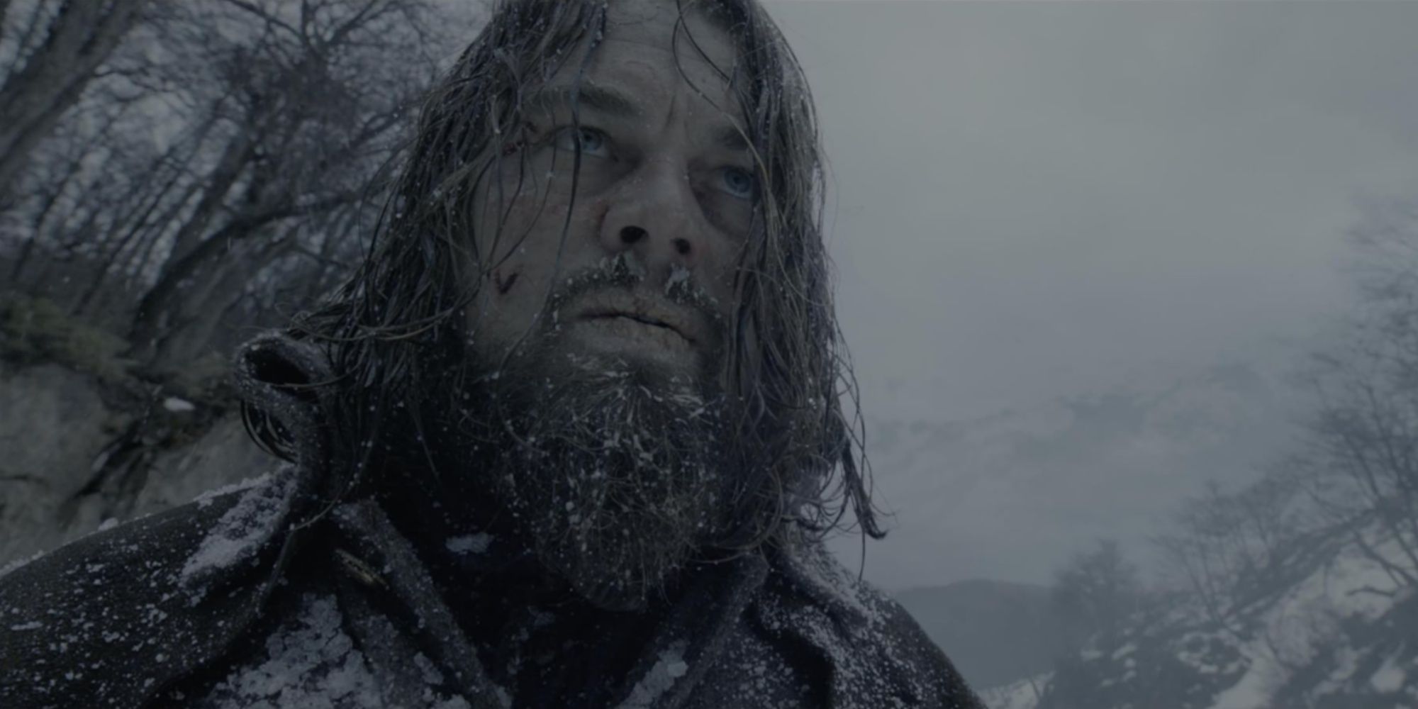 Close-up of Leonardi DiCaprio's character Hugh Glass in the freezing snow with a vengeful expression on his face.