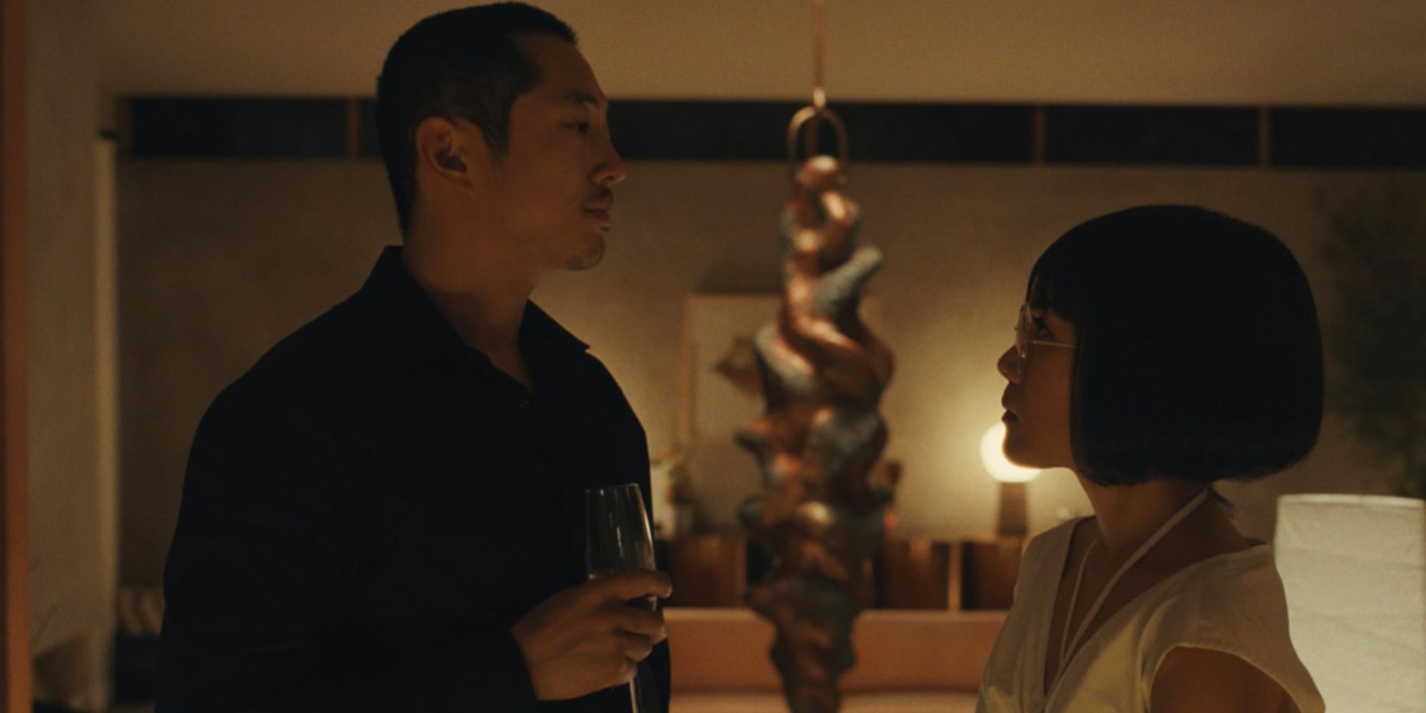 Steven Yeun's Danny Cho with a glass of champagne being confronted by Ali Wong's Amy Lau at a fancy party in Beef.