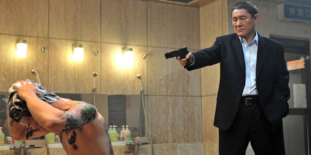 Character pointing a gun at a man without a shirt